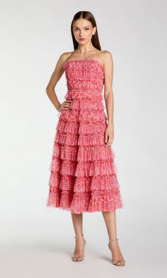 A woman stands in the Mac Duggal 8301—a yellow floral wedding-guest dress—against a plain light background.