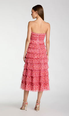 A woman facing away wears the Mac Duggal 8301 yellow floral wedding-guest dress, featuring a strapless design and tiered ruffles, paired with high-heeled sandals against a plain light background.