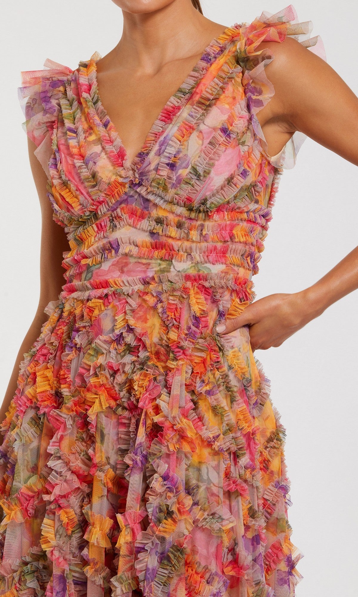 A woman wears the Long Formal Dress: Mac Duggal 8303, a sleeveless floral gown with a V-neckline and colorful ruffled fabric in vibrant shades of pink, orange, purple, and yellow.