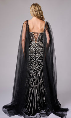 A woman in the Nina Canacci 8305 long formal dress, featuring silver geometric embellishments and a sheer black cape, stands facing away to reveal the lace-up back detail of her gown.