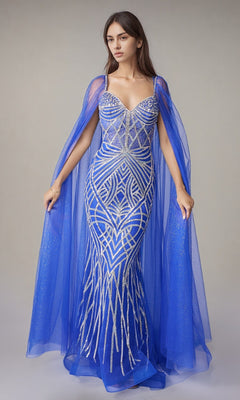 A woman models the Nina Canacci 8305 long formal dress in royal/silver, featuring a fitted geometric pattern, silver accents, cape sleeves, and a sheer blue cape, set against a neutral background.