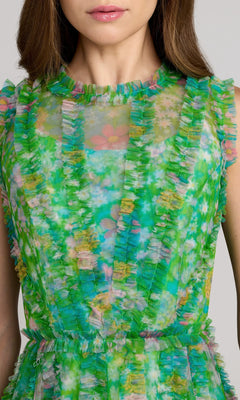 Woman wearing the Mac Duggal 8307 High-Neck Print Wedding-Guest Dress, a sleeveless green floral-print style with vertical ruffled details, shown from shoulders to waist.