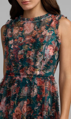 A woman wearing the Mac Duggal 8307 High-Neck Print Wedding-Guest Dress, featuring a floral print and sheer ruffled overlay—vibrant and perfect for any wedding guest.