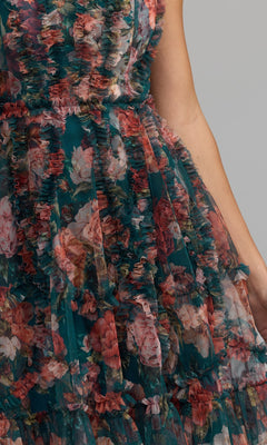 Close-up of a person in the Mac Duggal 8307 High-Neck Print Wedding-Guest Dress, featuring a sleeveless, ruffled tulle design with floral prints in green, pink, and red—ideal for making a statement at any wedding.