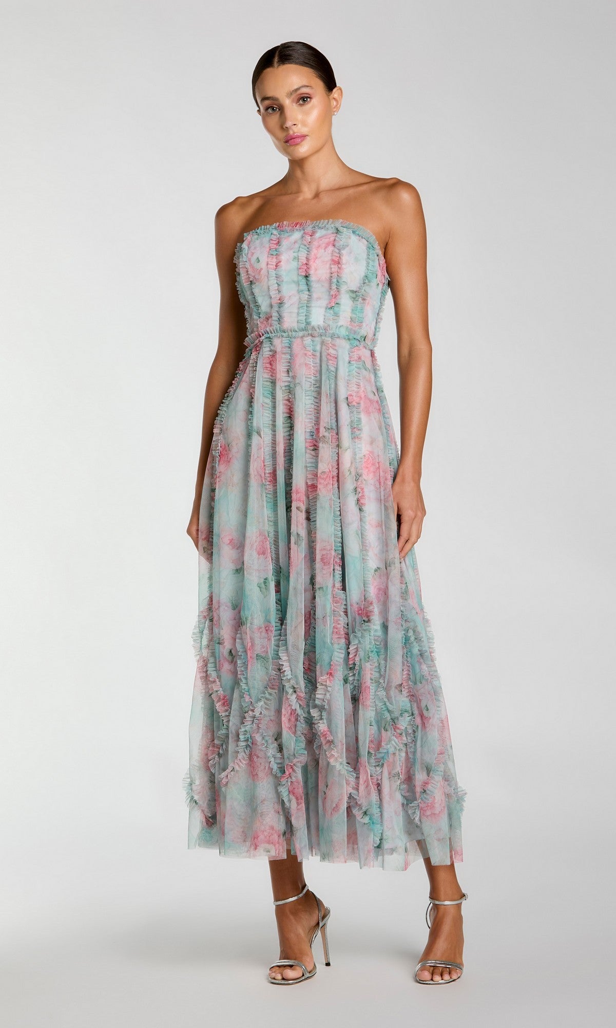 A woman stands against a plain background in silver high-heeled sandals, wearing the Mac Duggal 8308 Strapless Print Midi Party Dress featuring a floral print and ruffle details.