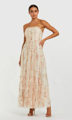 A woman wears the Mac Duggal 8308 Strapless Print Midi Party Dress, featuring a floral print and layered textured fabric, paired with open-toe high heels.