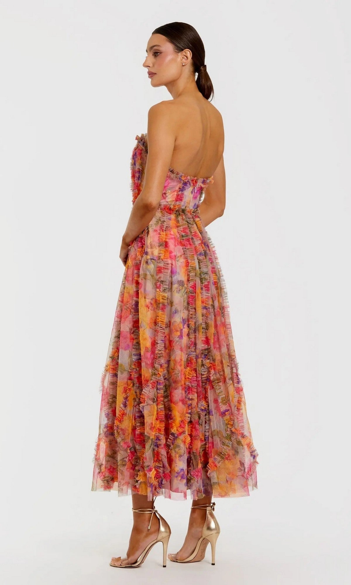Woman wearing the Mac Duggal 8308 Strapless Print Midi Party Dress with floral design and ruffle details, paired with gold high-heeled sandals, posed in side view against a plain light background.