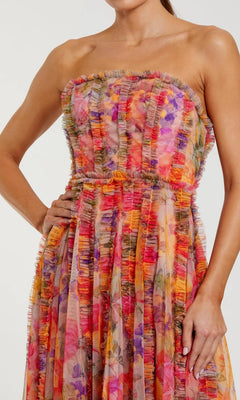A woman wearing the Mac Duggal 8308 Strapless Print Midi Party Dress, featuring a floral print, ruffled accents, and a fitted waist.