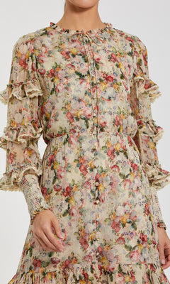 A person wearing the Mac Duggal 8334 Long Sleeve Ruffle Formal Dress, featuring floral print, ruffled sleeves, and lace trim, shown from shoulders to knees.