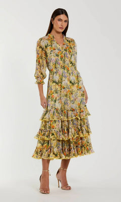 A woman wearing the Mac Duggal 8335 Midi Party Dress in Yellow Multi—a long, floral print party dress featuring ruffled details and three-quarter sleeves—paired with beige heeled sandals, standing against a plain background.