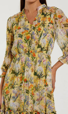 A woman wears the Mac Duggal 8335 Midi Party Dress, a yellow modest midi dress with long sleeves and a cinched waist, featuring a vibrant botanical print reminiscent of floral designs.