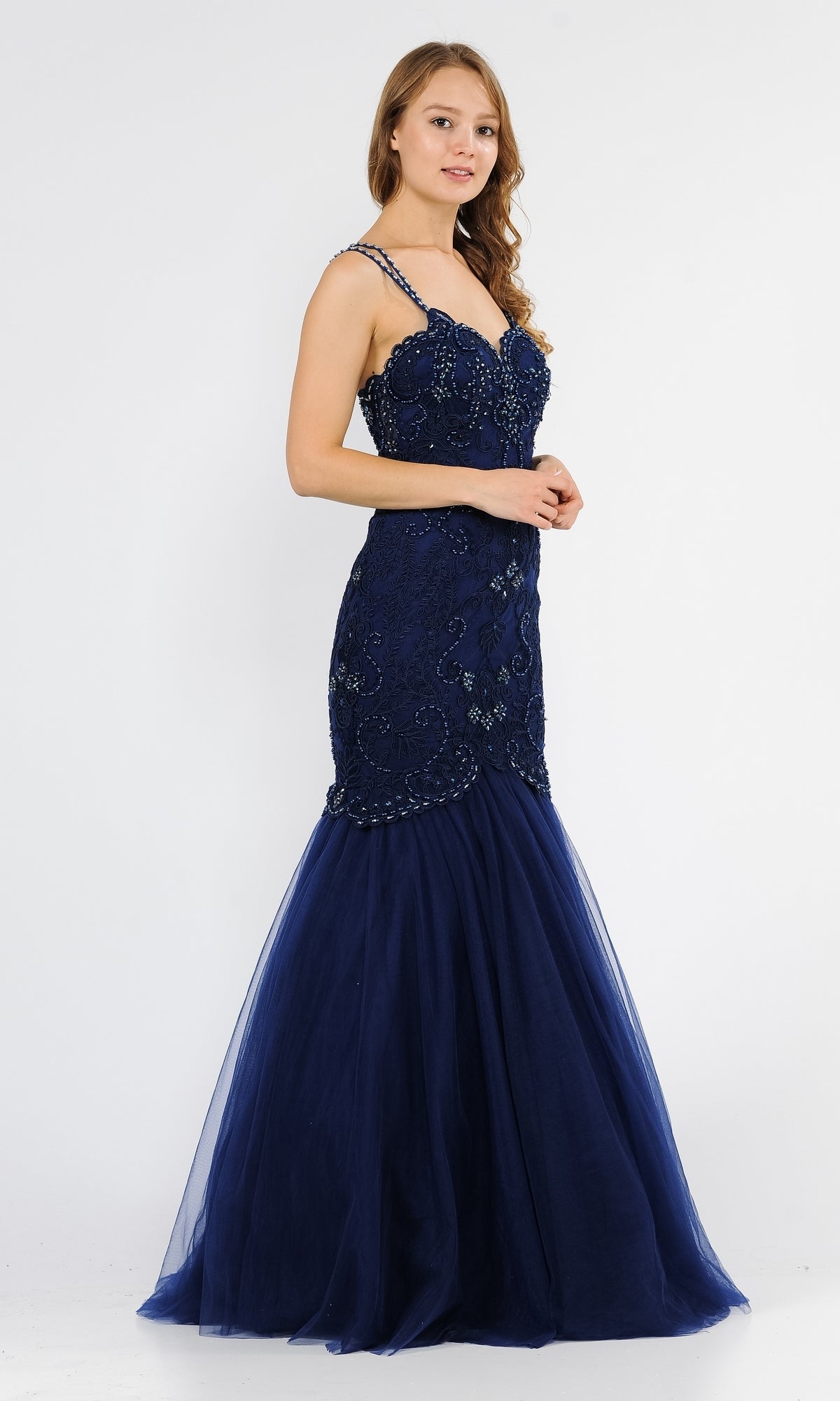 Woman wearing the Embroidered Tight Sweetheart Mermaid Prom Dress 8352, a navy blue, floor-length gown with bead embellishments and spaghetti straps, standing against a plain white background.
