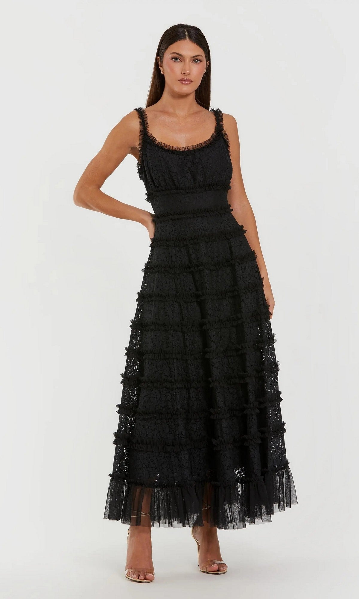 Model wearing the Mac Duggal 8372 Floral Lace Long Formal Dress—a sleeveless, black A-line gown with tiered lace and sheer hem, scoop neckline—posed in front of a plain white background.