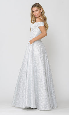 A woman stands in profile against a plain light background, wearing the Cold-Shoulder Silver and White Long Prom Gown 8380 with off-shoulder detailing, a textured finish, and her hand tucked in a pocket.
