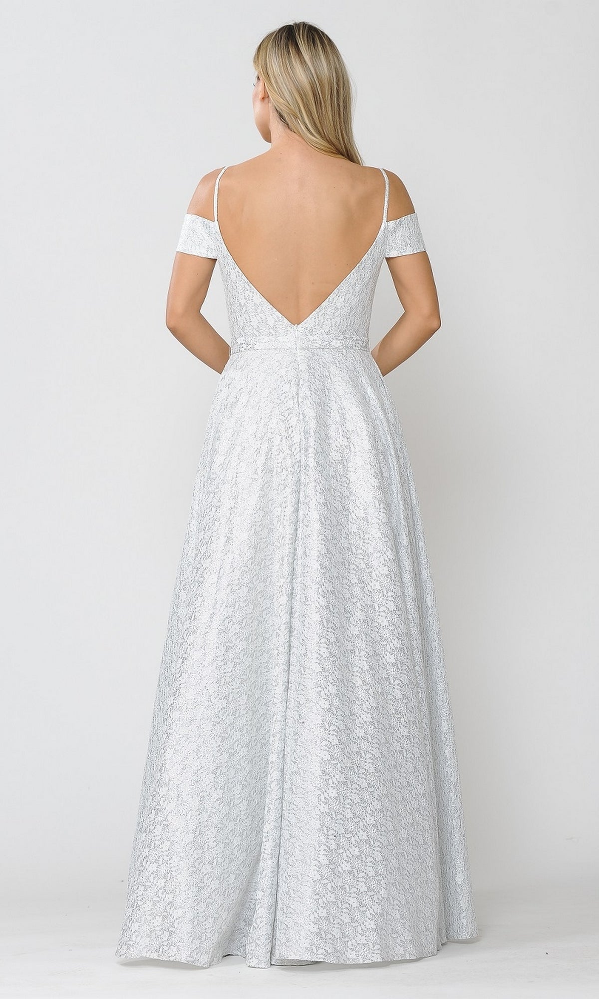 A woman with long blonde hair models the Cold-Shoulder Silver and White Long Prom Gown 8380, showcasing its floor-length, off-the-shoulder design and deep V-back as she stands facing away from the camera against a plain background.