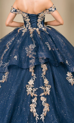A woman is seen from the back wearing the Quinceanera Dress 8390JQ by Cinderella Couture, an off-shoulder navy ball gown adorned with gold embroidery and glitter.