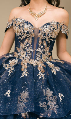 A woman wearing the Quinceanera Dress 8390JQ by Cinderella Couture—an off-the-shoulder navy ball gown adorned with gold floral embroidery, glitter accents, and paired with a gold statement necklace.