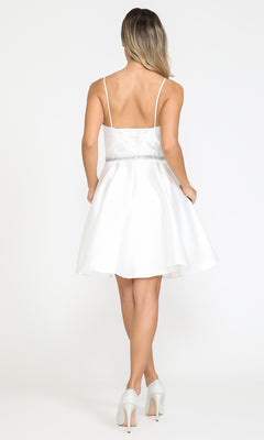 A woman in the Short Mikado Homecoming Dress 8420 with pockets and thin straps, paired with silver heels, stands facing away against a white background. This stylish party dress is available for under $150.