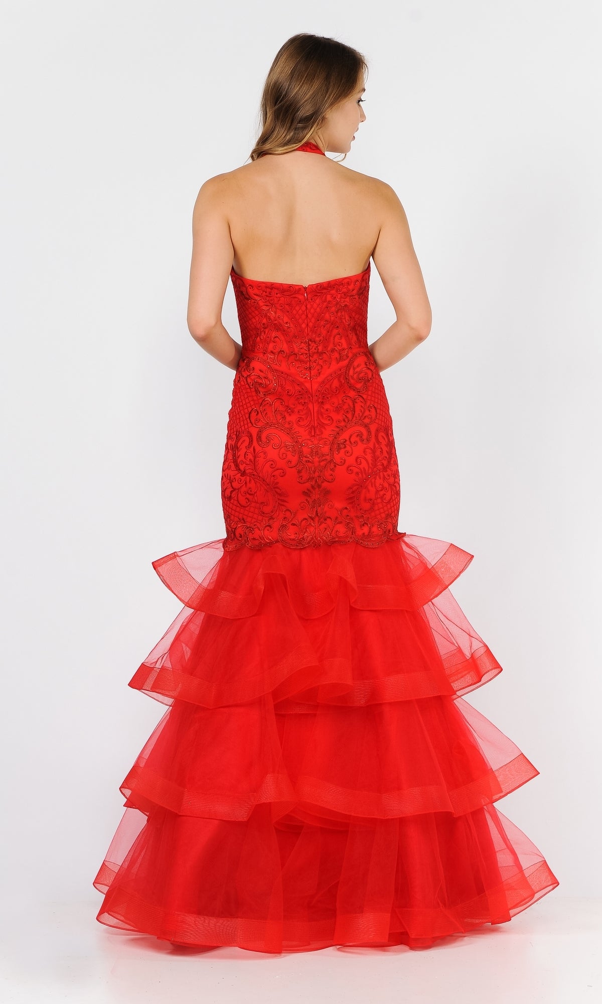 A woman in the Beaded Long Halter Mermaid Tiered Prom Dress 8466, featuring beaded details and tiered layers, stands facing away from the camera against a white background.