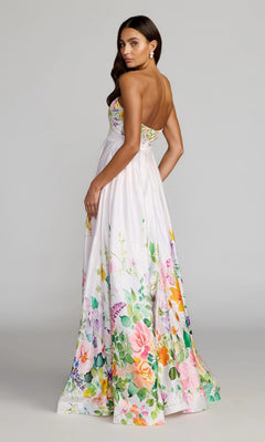 A woman wearing the Mac Duggal 8470 Long Formal Dress, a striking strapless satin gown featuring vibrant floral patterns, looks over her shoulder against a plain background.