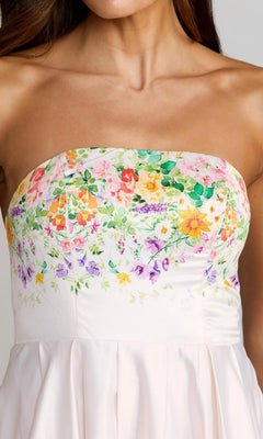 A woman wearing the Long Formal Dress: Mac Duggal 8470—a strapless floral formal gown featuring a beautifully detailed bodice and a light pink, pleated skirt—captures the stunning elegance of iconic Mac Duggal designs.