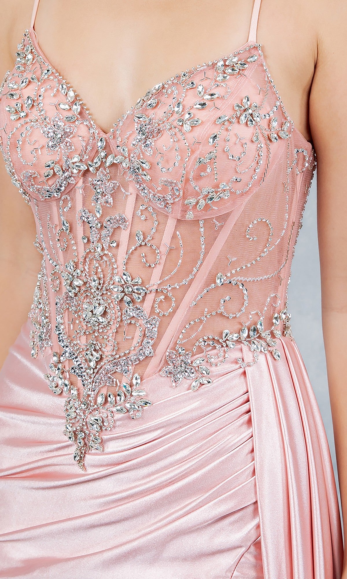 Close-up of the Cinderella Couture 8483J long prom dress in pink satin, showcasing a sheer corset bodice with silver beading, rhinestone accents, and a ruched draped skirt.