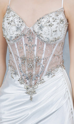A close-up of the Long Prom Dress: Cinderella Couture 8483J, showcasing its white satin fabric, sheer corset bodice with intricate beaded embroidery, delicate silver details, and thin straps.