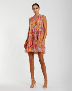 A woman wearing the Mac Duggal 8488 Short Party Dress in Multi—a sleeveless mini with a ruffled silhouette and vibrant floral pattern—pairing it with strappy high-heeled sandals against a plain background for a chic, signature look.