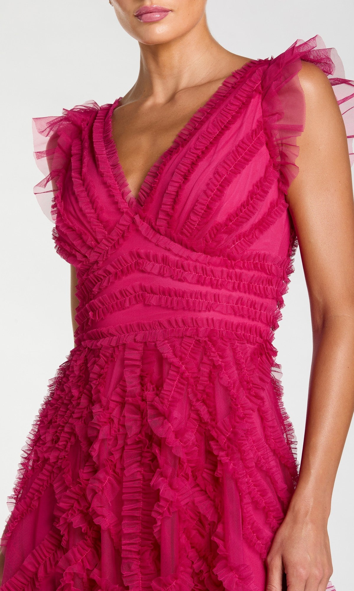 A woman wearing the Mac Duggal 8498 long formal dress, featuring a sleeveless fuchsia design with ruffled, textured details, a V-neckline, and an A-line silhouette, shown from shoulders to mid-thigh.