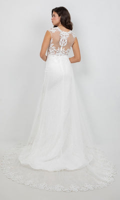 A woman models the Long Formal Dress: Cinderella Couture 8506J, a floor-length white wedding gown featuring lace applique detailing on the back and a sheer tulle train, standing against a plain white background.