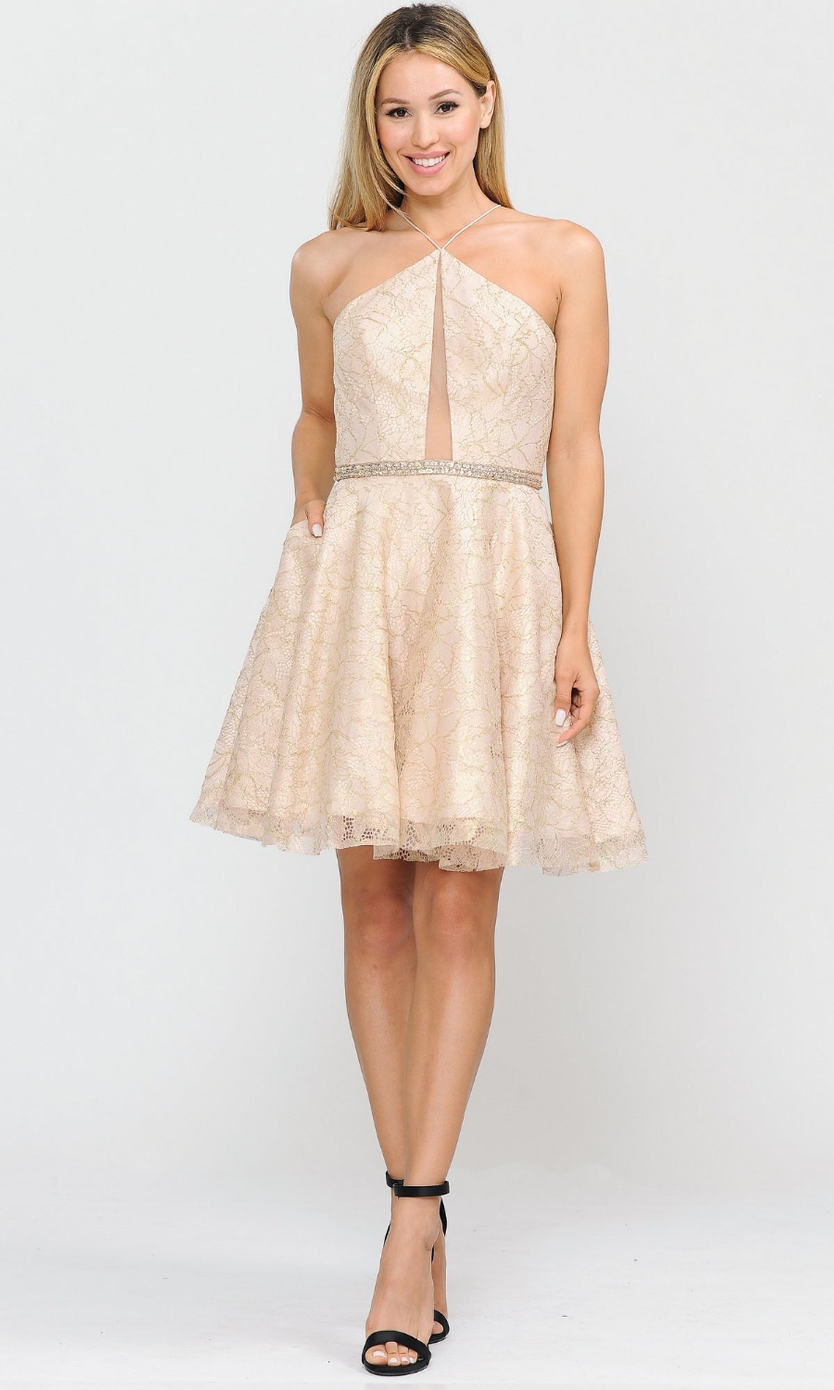 Wearing the Glitter-Mesh Short A-Line Homecoming Dress 8506, a sleeveless beige lace dress with a halter neckline and beaded waist, styled with black heels—an elegant option for any special event.
