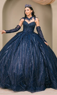 A woman wearing the Quinceanera Dress 8510JQ by Cinderella Couture in navy, adorned with sequin embellishments, along with matching gloves, necklace, and tiara, stands indoors against a neutral background.