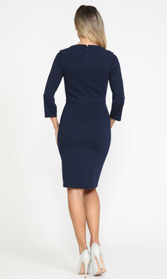 A woman faces away, wearing the Classy Knee-Length Career Dress 8526 with three-quarter sleeves and light-colored heels, showcasing a modest style against a plain white background.