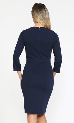 A woman with long, wavy hair is pictured from behind wearing the Classy Knee-Length Career Dress 8526—a fitted navy blue modest dress with three-quarter sleeves, perfect for a professional look.