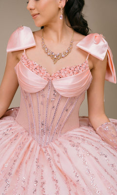 A woman wearing the Quinceanera Dress 8530JQ by Cinderella Couture, a pink sequined ball gown featuring satin bows on the shoulders and a beaded corset bodice, accessorized with a jeweled necklace and matching earrings, shown from the shoulders to the waist.