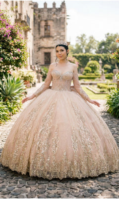 A young woman in the Quinceanera Dress 8545JQ By Cinderella Couture, featuring an off-the-shoulder sweetheart neckline and beaded sequin embellishments, stands on a garden stone path with a historic building in the background.