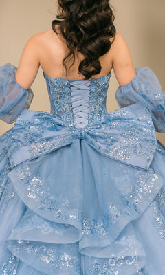 Back view of the blue Quinceanera Dress 8565JQ By Cinderella Couture, a strapless ball gown with a lace-up back, removable puff sleeves, and a large bow with silver sequin floral embroidery.