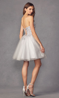 A woman wearing the Embroidered-Corset Babydoll Homecoming Dress 860 with a silver tulle skirt, lace-up back, and silver high-heeled sandals stands against a plain gray background.