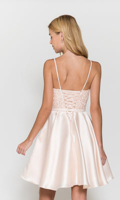 Woman in the Short A-Line Homecoming Dress with Pockets 8694—light pink satin, thin straps, lace-up back, and flared skirt—stands facing away from the camera.