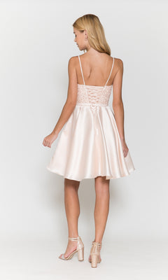 A woman with blonde hair faces away, wearing the Short A-Line Homecoming Dress with Pockets 8694 in light pink satin. The dress features a lace-up corset back and flared skirt, paired with heeled sandals.