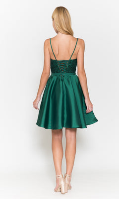 A woman faces away, wearing the Short A-Line Homecoming Dress with Pockets 8694 in green, featuring a lace-up back and flared skirt, paired with light-colored heeled shoes.