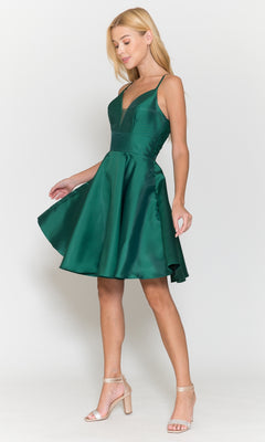 A woman in the Lace-Back Short A-Line Homecoming Dress 8698—sleeveless, deep green with a V-neck and knee-length hem—stands against a plain white background, paired with strappy heels.