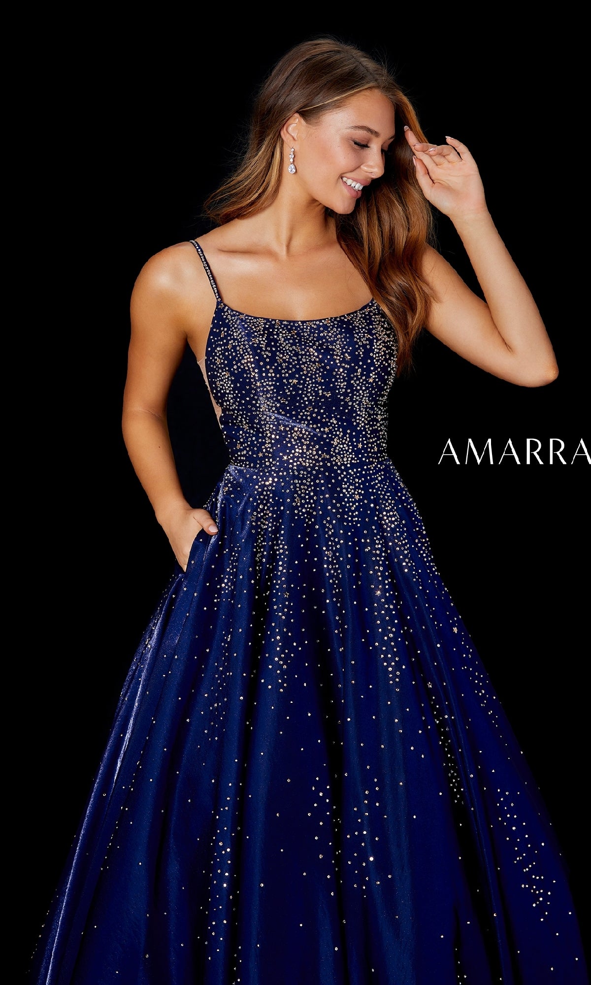 A woman poses against a plain black background wearing the Amarra 87292 long prom dress?sleeveless, navy blue, with glittering embellishments and a satin A-line skirt. 