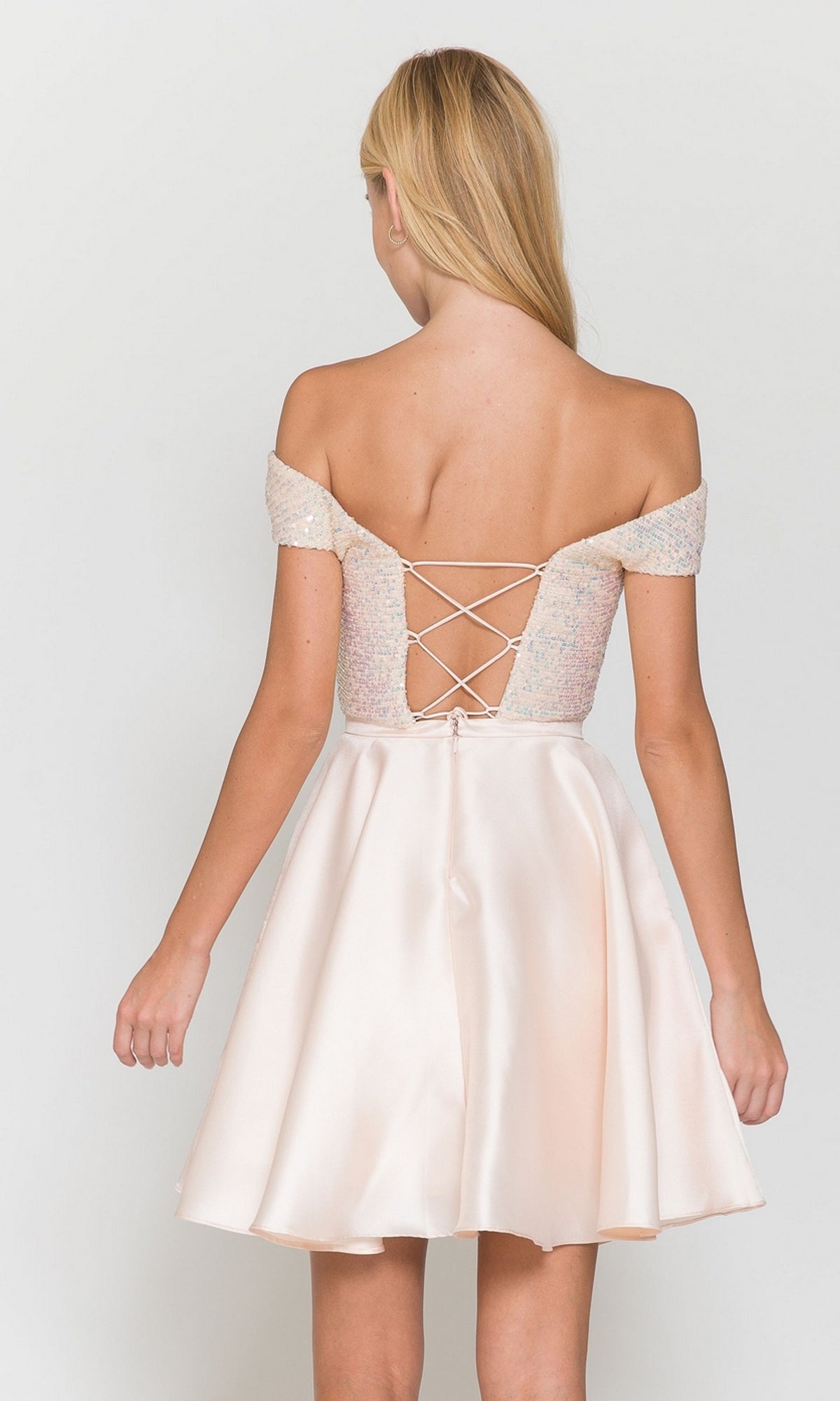 A young woman models the Cap-Sleeve Short A-Line Homecoming Dress 8732, featuring light pink satin with a lace-up corset back, cap sleeves, and a flared skirt, standing against a plain background.