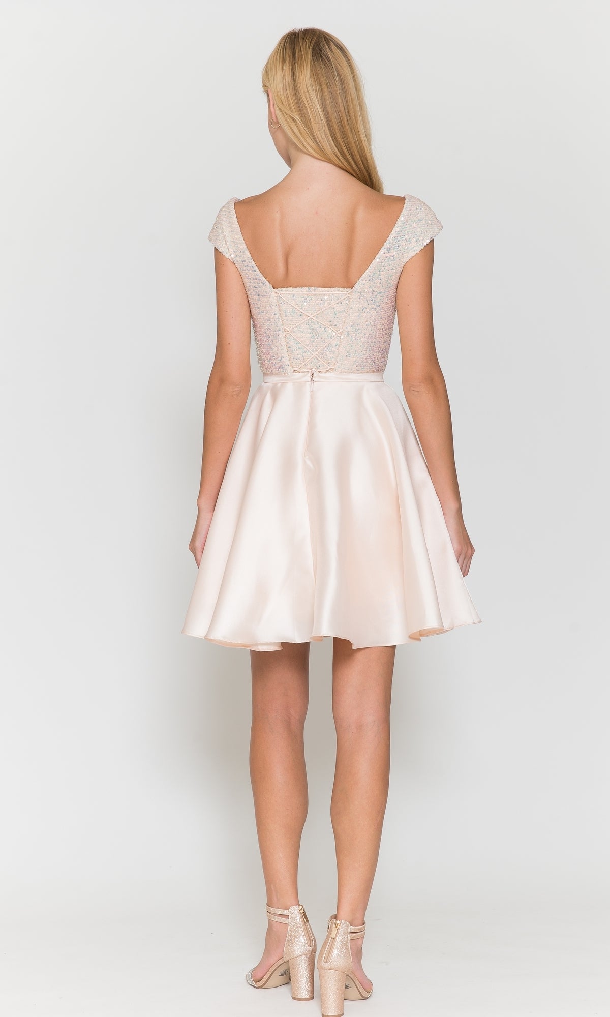 Woman with her back to the camera wears the Cap-Sleeve Short A-Line Homecoming Dress 8732 in light pink and metallic heels, posing against a plain white background.