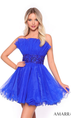 A woman models the Short Homecoming Dress 88038 by Amarra, a royal blue strapless dress with a ruffled bodice and beaded waist, against a white background.