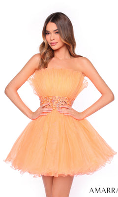Model in the Amarra Short Homecoming Dress 88038, a strapless, peach mini dress with a beaded waist, stands with hands on hips against a white background.