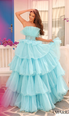 A woman stands outdoors near a white bench and purple door, wearing the Long Formal Dress 88083 by Amarra?a strapless gown with a beaded waist and layered light blue skirt.