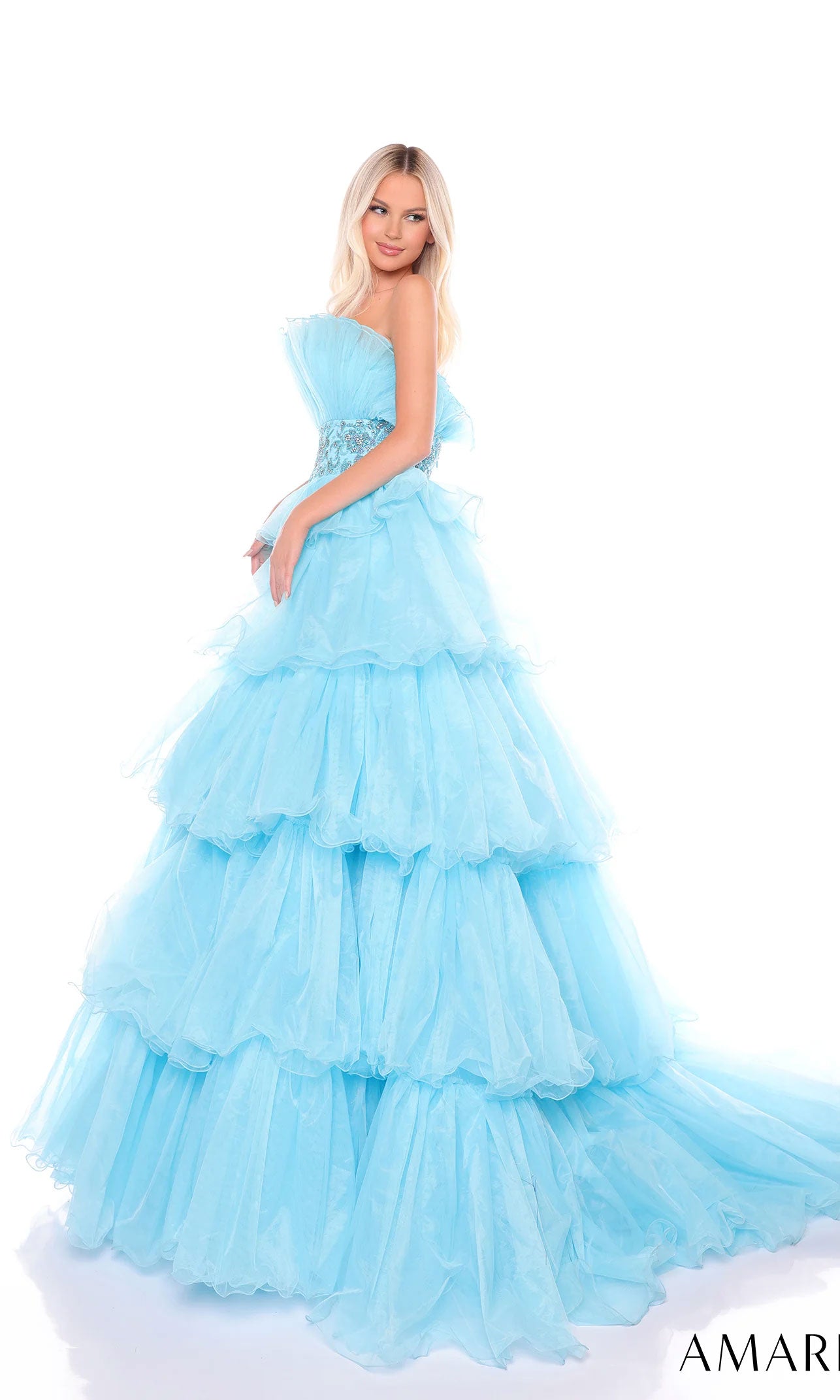 A woman poses in the Long Formal Dress 88083 by Amarra, featuring a strapless fitted bodice, beaded waist, and ruffled layers, set against a white background.