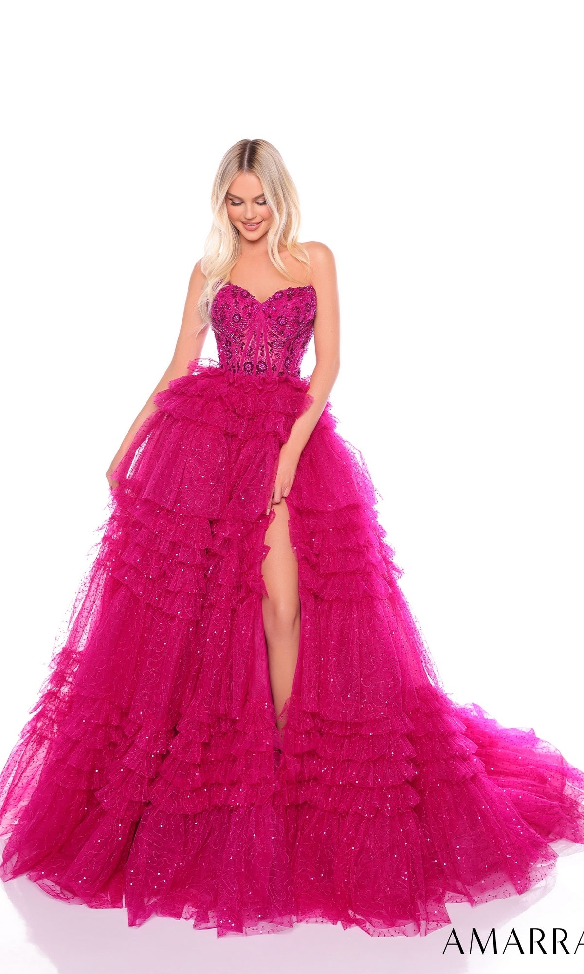 Woman models the Long Formal Dress 88099 by Amarra—a bright pink, strapless ball gown with ruffle layers and a high slit—standing against a white background.